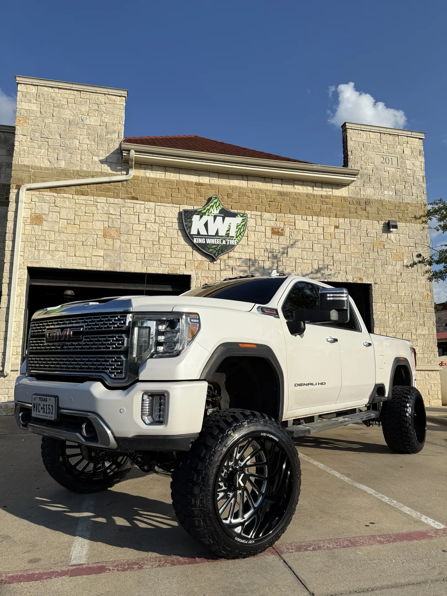 A lifted white GMC Denali HD parked in front of the King Wheel & Tire shop in Mansfield, TX
