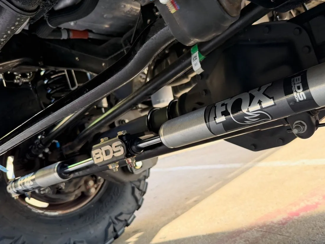 A FOX shock and BDS hardware under a lifted truck in the bay