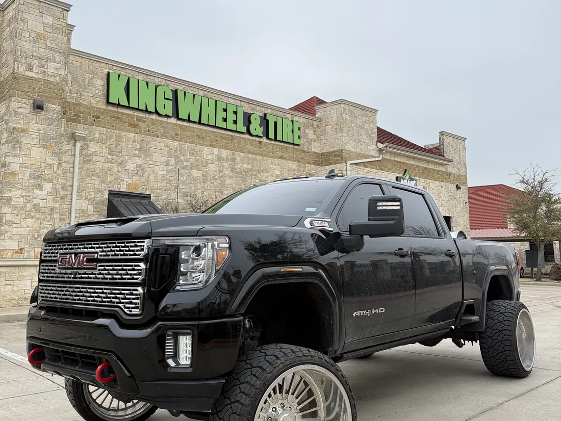A lifted black GMC Sierra AT4 HD on forged wheels in front of King Wheel & Tire in Mansfield, TX
