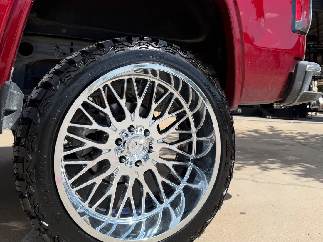 A polished multi-spoke custom wheel on a red truck